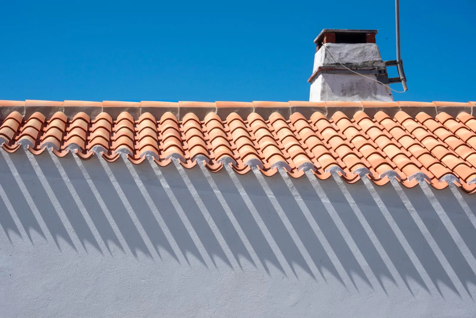 Restored terracotta tile roof with a clean ridge line against a blue sky